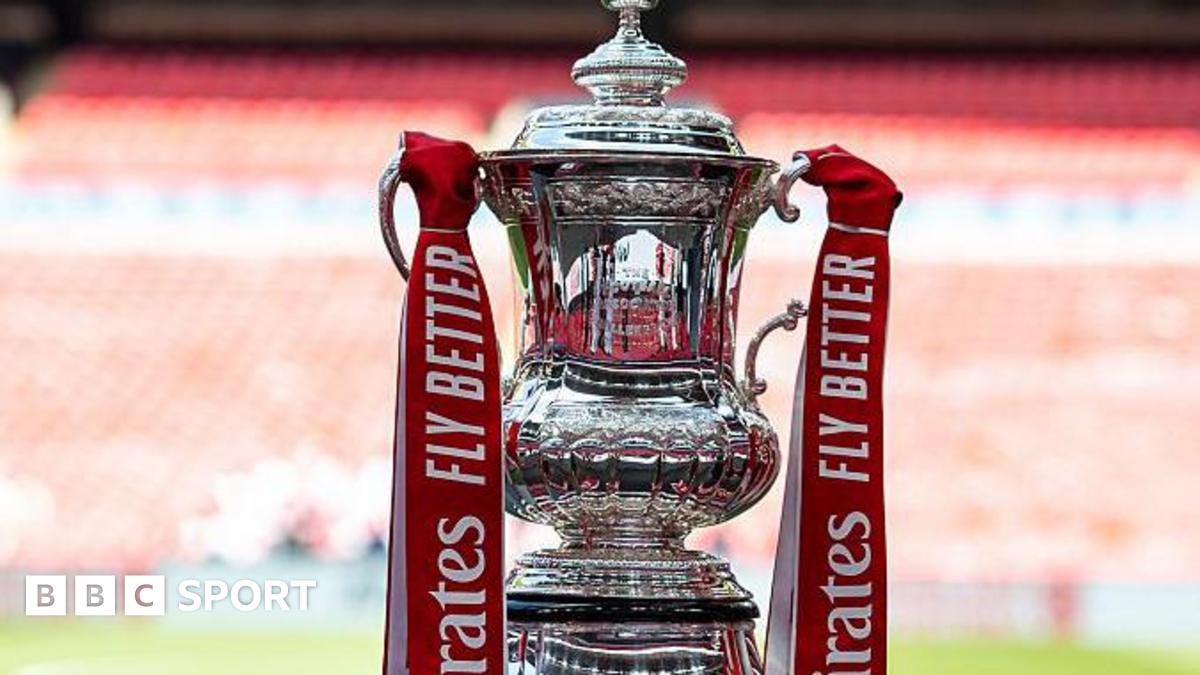 The FA Cup trophy, with red ribbons containing the sponsor