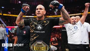 Alex Pereira flexing his biceps with the light-heavyweight UFC title around his waist