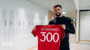 Bruno Fernandes holds up a shirt in the Manchester United dressing room