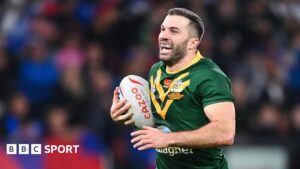 James Tedesco in an Australia jersey running from right to left with the ball, his mouth open to reveal a branded mouthguard