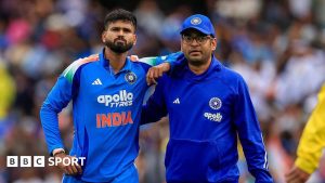 Shreyas Iyer (left) is helped from the field by a member of India