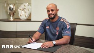 Vincent Kompany sits at a table and signs a piece of paper